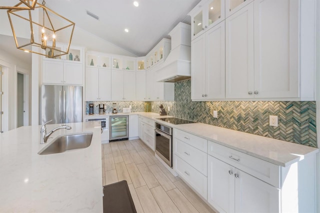 kitchen featuring premium range hood, wine cooler, sink, decorative light fixtures, and appliances with stainless steel finishes