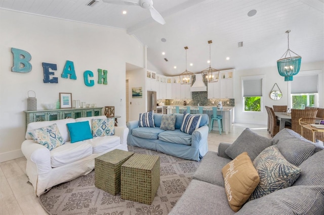 living room featuring ceiling fan with notable chandelier, beam ceiling, high vaulted ceiling, and light wood-type flooring