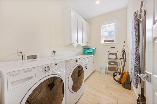 laundry area featuring cabinets, washing machine and clothes dryer, and light hardwood / wood-style flooring