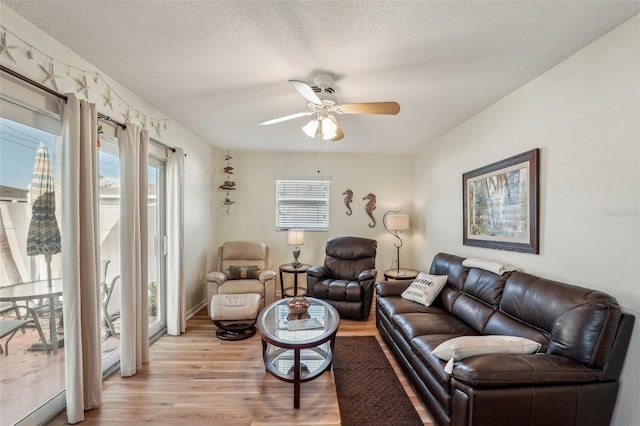 living room featuring ceiling fan, a textured ceiling, and light wood-type flooring