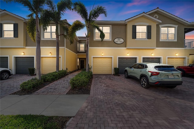 multi unit property featuring driveway, an attached garage, and stucco siding