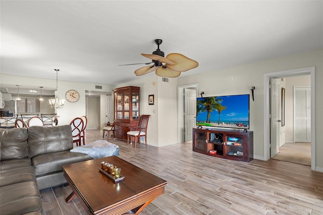 living room featuring ceiling fan with notable chandelier and light hardwood / wood-style floors