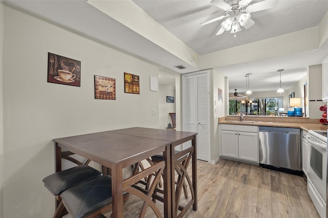 dining area with ceiling fan, sink, and light hardwood / wood-style flooring