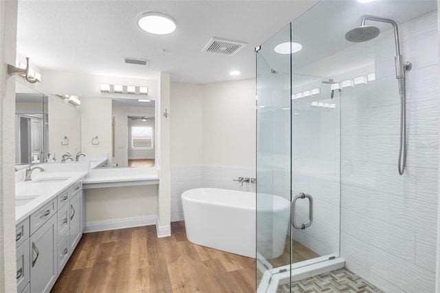 bathroom featuring independent shower and bath, wood-type flooring, tile walls, and vanity