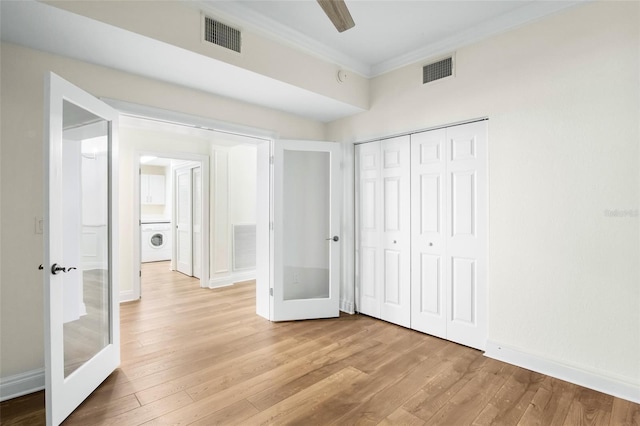 unfurnished bedroom featuring french doors, light hardwood / wood-style flooring, ornamental molding, a closet, and washer / clothes dryer