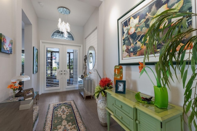 foyer entrance with dark wood-type flooring, a chandelier, and french doors