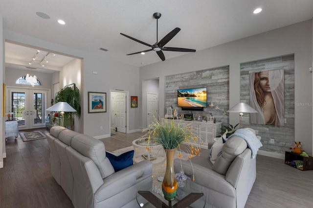 living room featuring ceiling fan with notable chandelier, hardwood / wood-style floors, and french doors