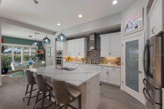 kitchen with white cabinets, appliances with stainless steel finishes, sink, and wall chimney range hood