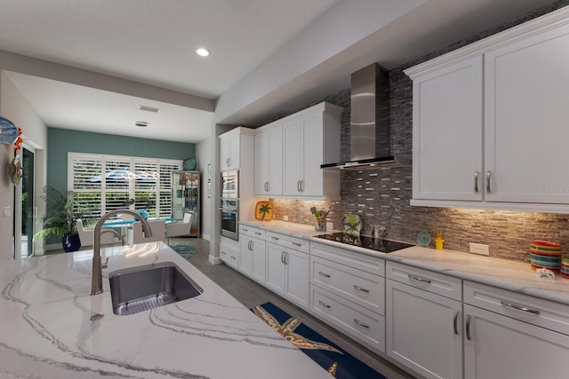 kitchen featuring white cabinetry and wall chimney range hood