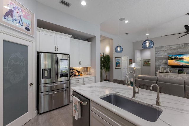 kitchen featuring light stone countertops, white cabinetry, appliances with stainless steel finishes, and sink