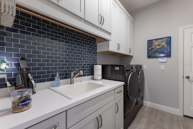 laundry room with light hardwood / wood-style floors, cabinets, separate washer and dryer, and sink