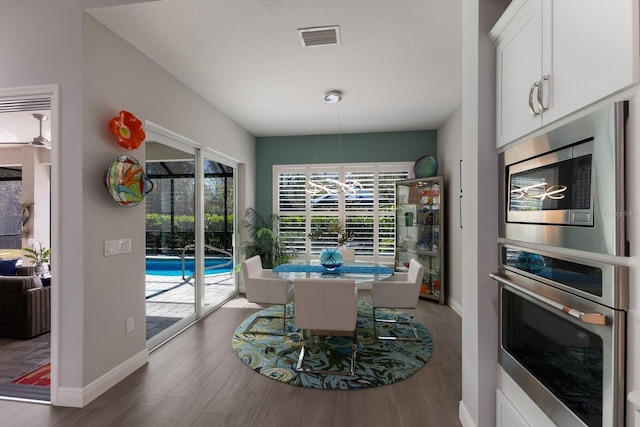 dining space with dark hardwood / wood-style floors, a textured ceiling, and a wealth of natural light