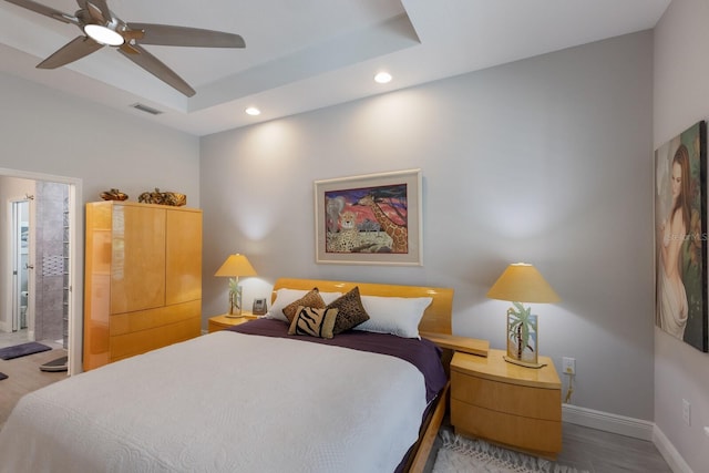 bedroom featuring hardwood / wood-style floors, a raised ceiling, and ceiling fan