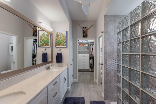 bathroom featuring hardwood / wood-style flooring, ceiling fan, vanity, and a tile shower