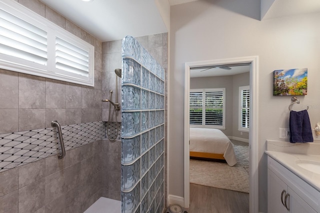 bathroom with wood-type flooring, a tile shower, and vanity