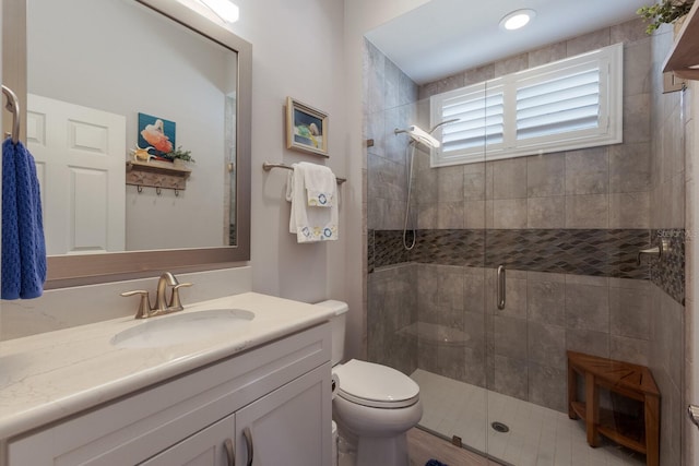 bathroom with a shower with door, vanity, and toilet