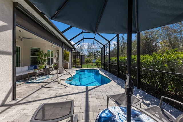 view of pool with an outdoor living space, a patio, ceiling fan, and glass enclosure