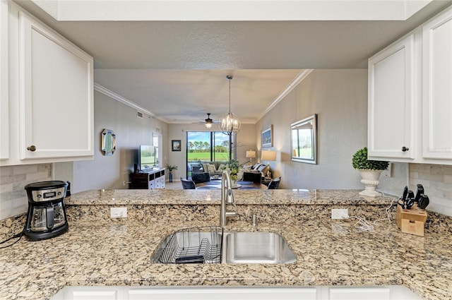 kitchen featuring open floor plan, ornamental molding, and white cabinetry