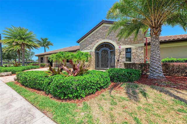 view of front of home featuring stone siding, a tiled roof, and stucco siding