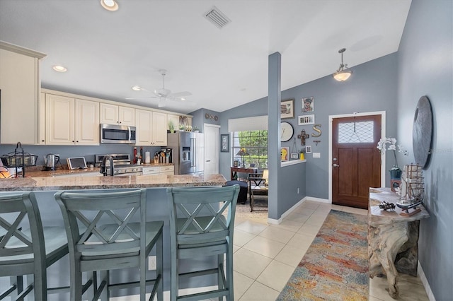 kitchen with decorative light fixtures, light tile patterned floors, kitchen peninsula, stainless steel appliances, and cream cabinets