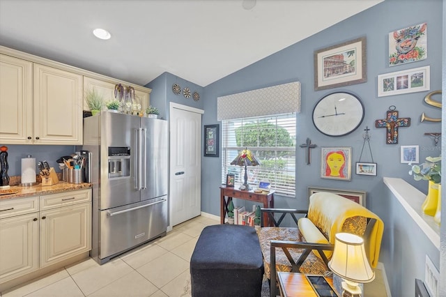 kitchen with cream cabinets, light stone countertops, light tile patterned flooring, vaulted ceiling, and high end refrigerator