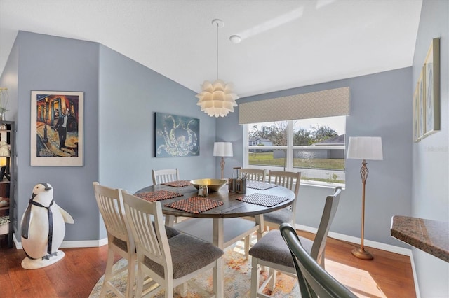 dining area with wood-type flooring and vaulted ceiling