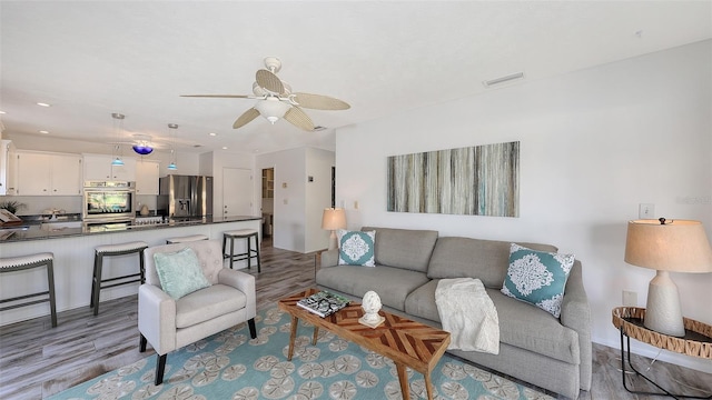 living room featuring ceiling fan and light hardwood / wood-style floors