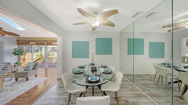 dining room featuring ceiling fan, a skylight, and hardwood / wood-style floors