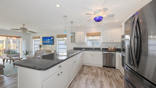 kitchen with stainless steel appliances, sink, white cabinets, and kitchen peninsula