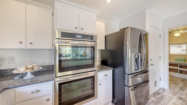 kitchen with stainless steel appliances, white cabinets, and dark stone counters