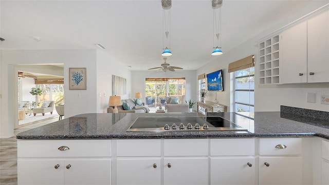 kitchen featuring white cabinetry, dark stone counters, decorative light fixtures, and cooktop