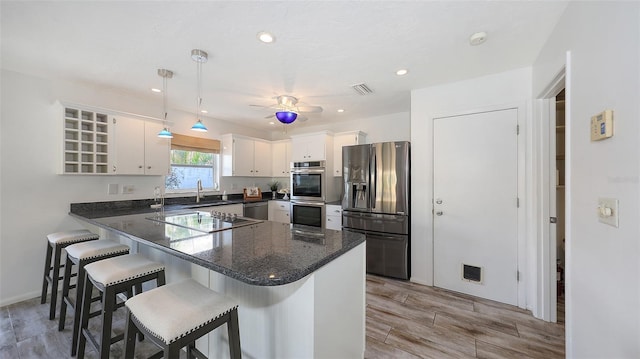 kitchen with sink, appliances with stainless steel finishes, white cabinetry, hanging light fixtures, and kitchen peninsula