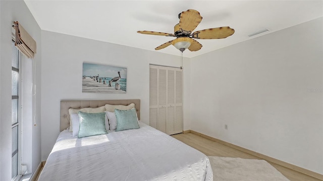 bedroom with light wood-type flooring, ceiling fan, and a closet