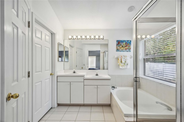 bathroom with a relaxing tiled tub, vanity, and tile patterned flooring