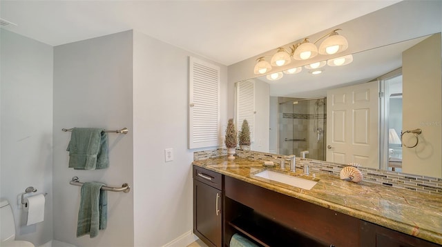 bathroom featuring toilet, vanity, a shower with shower door, and decorative backsplash