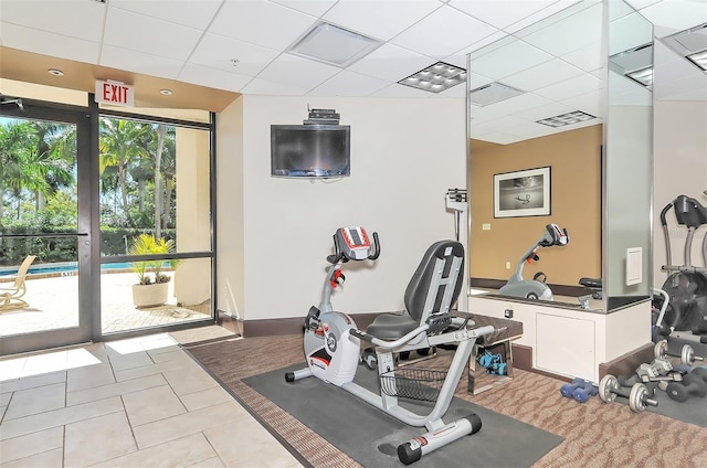 exercise room with expansive windows, light tile patterned flooring, and a drop ceiling