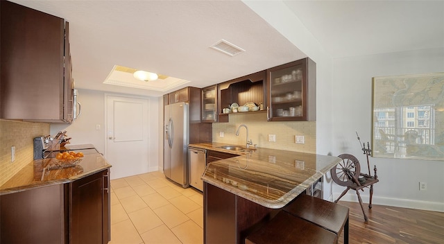 kitchen featuring kitchen peninsula, sink, tasteful backsplash, appliances with stainless steel finishes, and a kitchen breakfast bar