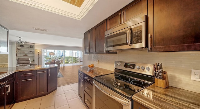 kitchen with dark brown cabinets, light tile patterned floors, tasteful backsplash, and stainless steel appliances