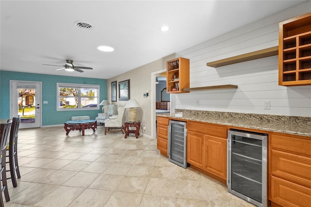 kitchen featuring wine cooler, ceiling fan, light tile patterned floors, and light stone countertops