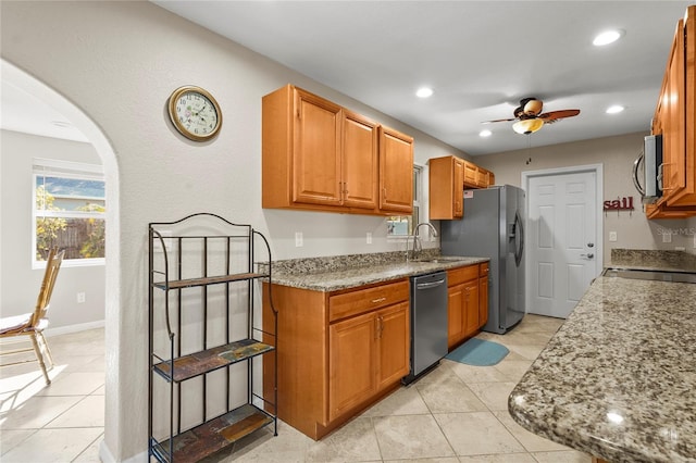 kitchen featuring ceiling fan, appliances with stainless steel finishes, sink, and light stone counters