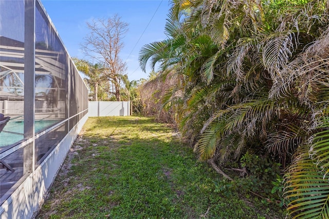 view of yard featuring a fenced in pool and glass enclosure