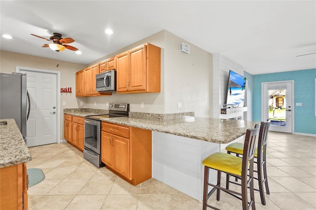 kitchen featuring ceiling fan, a kitchen breakfast bar, a peninsula, recessed lighting, and stainless steel appliances