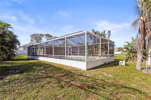 back of property with an outdoor pool, a lawn, and a lanai