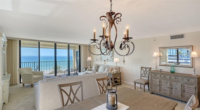 dining room featuring a water view, light colored carpet, and a chandelier