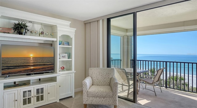 sitting room featuring light carpet, a view of the beach, and a water view