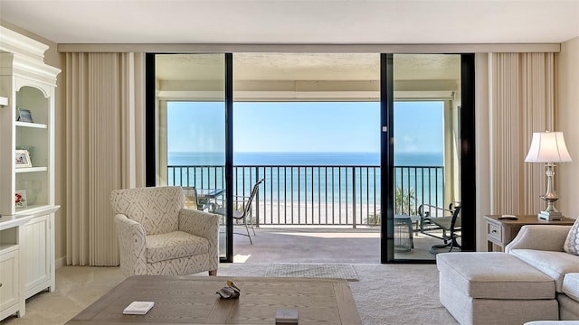 carpeted living room featuring floor to ceiling windows, a water view, and a beach view