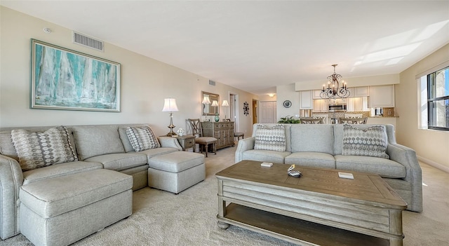 carpeted living room featuring a notable chandelier