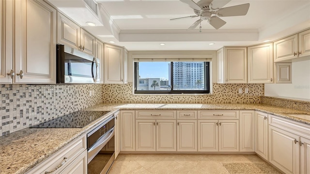 kitchen featuring crown molding, appliances with stainless steel finishes, light stone counters, and cream cabinetry