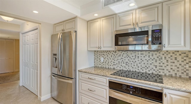 kitchen featuring appliances with stainless steel finishes, built in desk, backsplash, and light stone counters