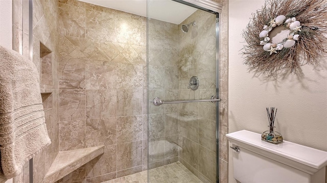 bathroom featuring toilet and a shower with shower door